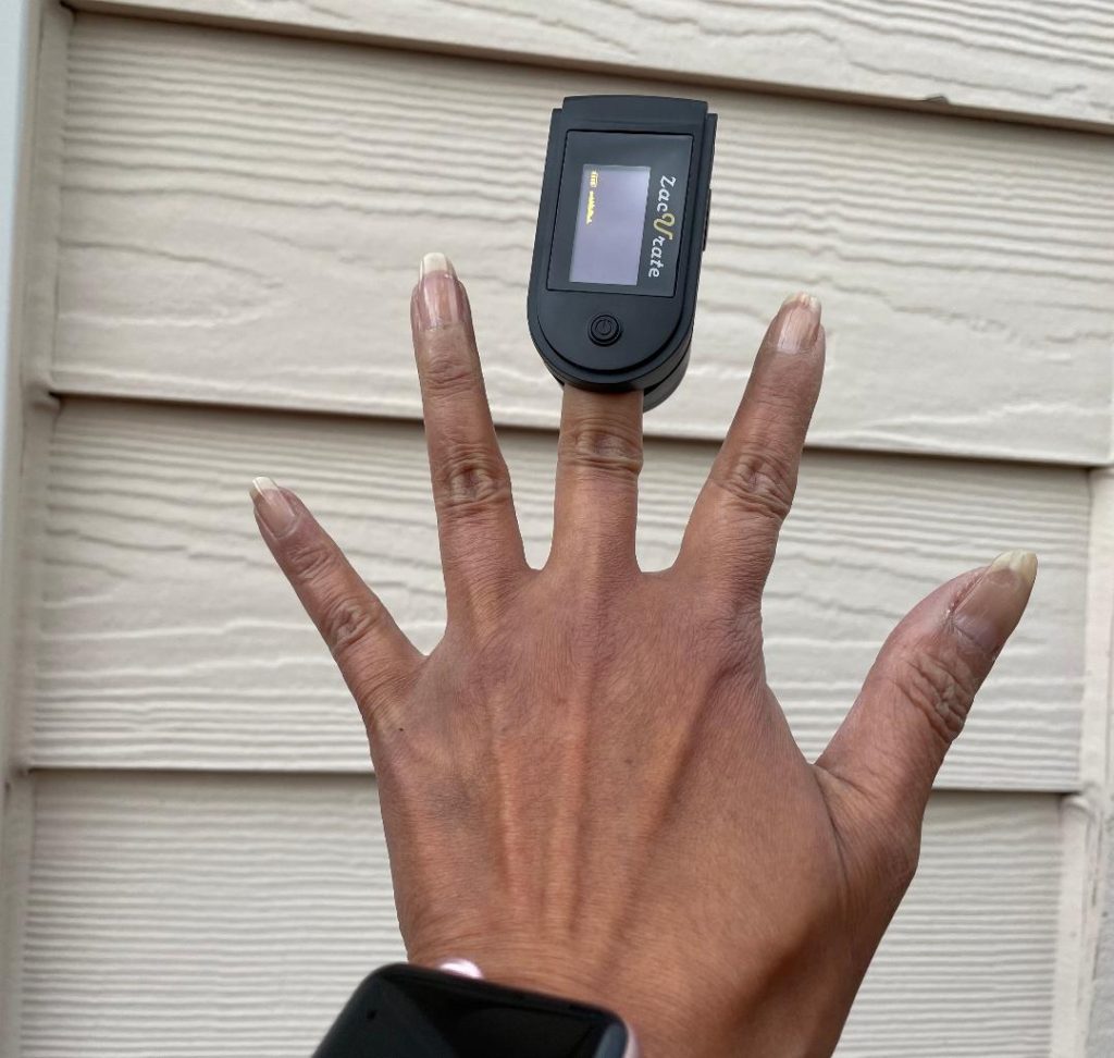Finger pulse oximeter on a brown hand